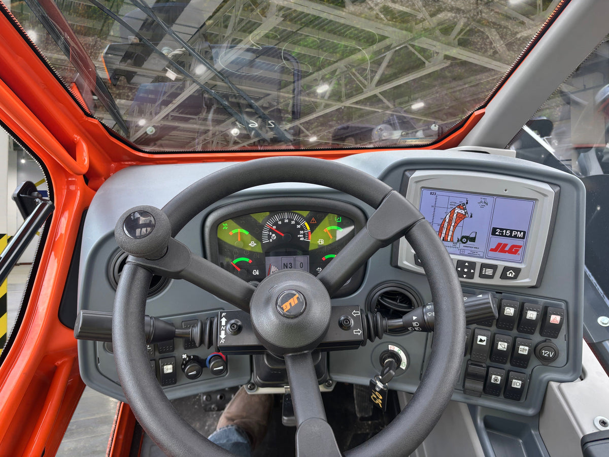 Interior view of a 2024 JLG 823 Ag Telehandler cabin featuring the steering wheel, digital display, and controls.